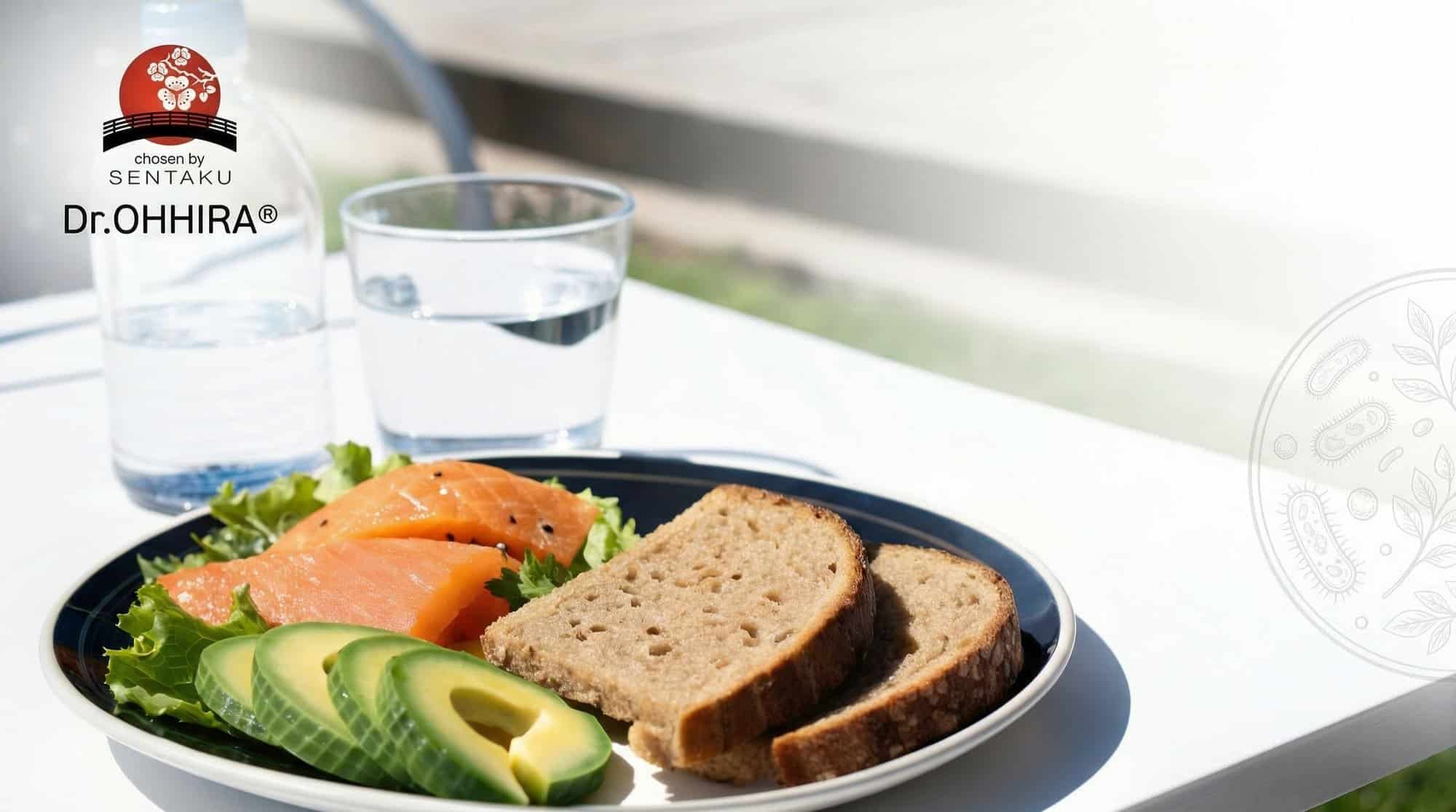 На тарелке - лосось, авокадо, салат и хлеб, рядом - бутылка с водой и стакан воды.
