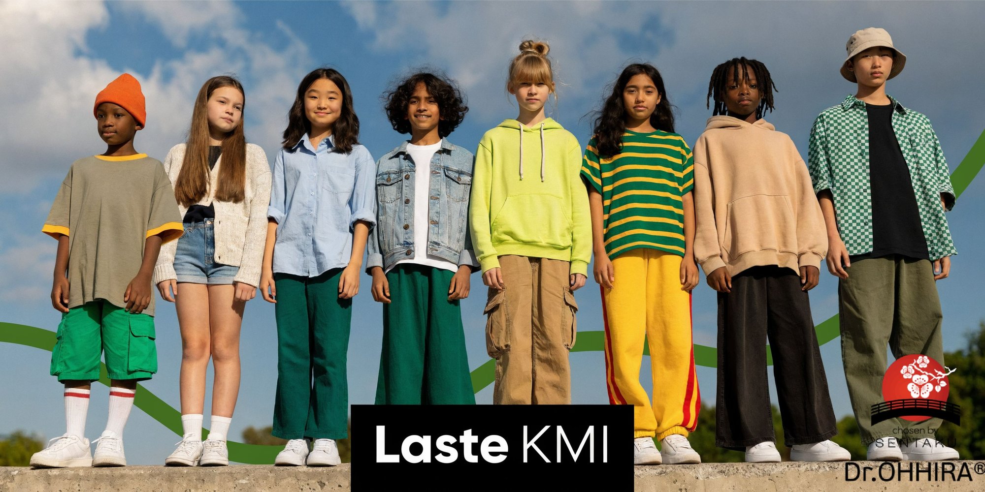 Seitse eri rahvusest last, kes on riietatud värvilistesse rõivastesse, seisavad õues seina peal sinise taeva taustal.