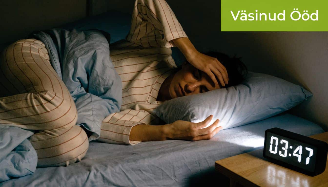 Valgustatud äratuskell näitab öösel kellaaega, samal ajal kui väsinud inimene voodis unetult pead hoiab.